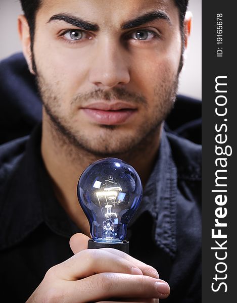 Young man with light bulb in his hands and looking in camera