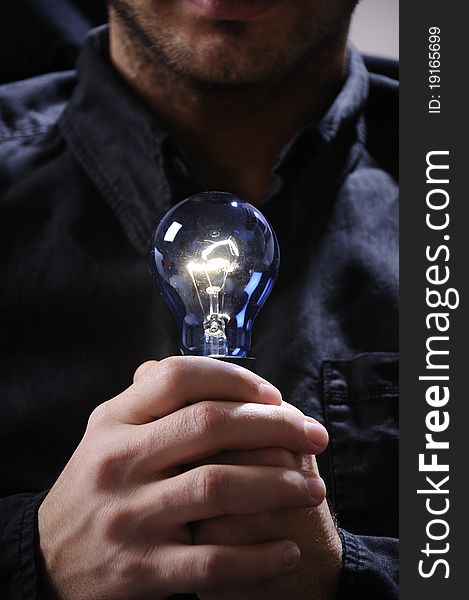 Young man with light bulb in his hands and looking in camera