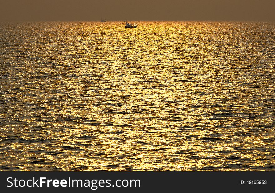 Golden sea with a little boat from afar