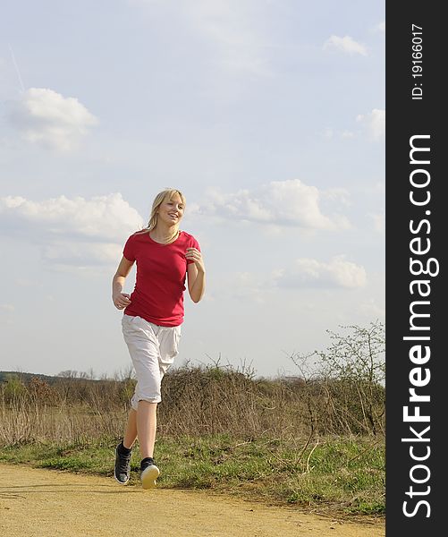 Young woman jogging on a dirt road