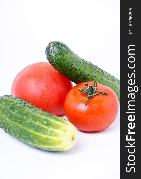 Fresh green cucumbers and two tomatos isolated on white. Fresh green cucumbers and two tomatos isolated on white