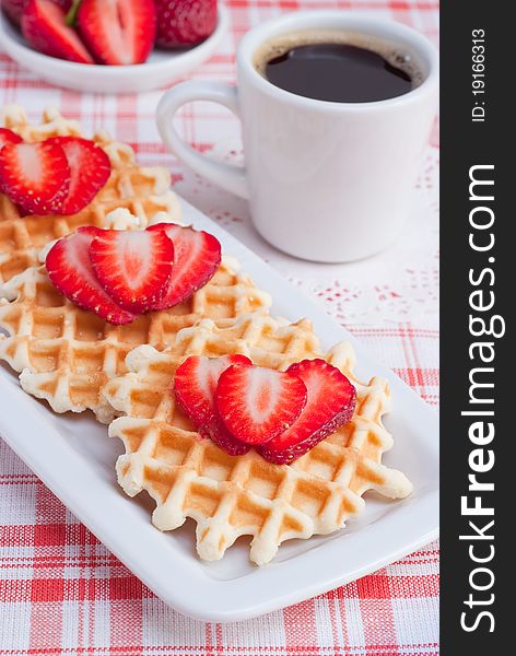 Gold, tasty waffles with ripe strawberry and cup of coffee, selective focus. Gold, tasty waffles with ripe strawberry and cup of coffee, selective focus.