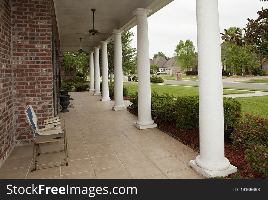 Angular view of front porch with white columns and ceiling fans overhead