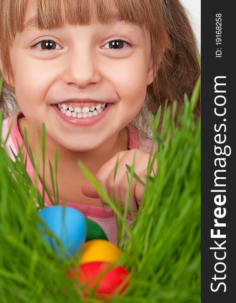 Little girl finds a multicoloured easter eggs in the tall green grass. Little girl finds a multicoloured easter eggs in the tall green grass