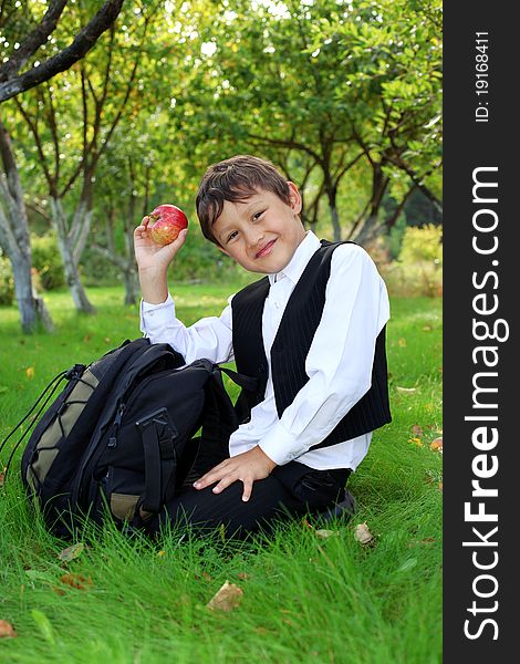 Schoolboy with backpack and apple outdoors