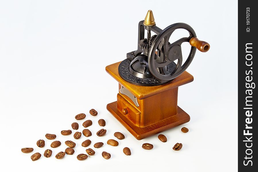 Antique wooden coffee grinder with a white background with spilled coffee. Antique wooden coffee grinder with a white background with spilled coffee.
