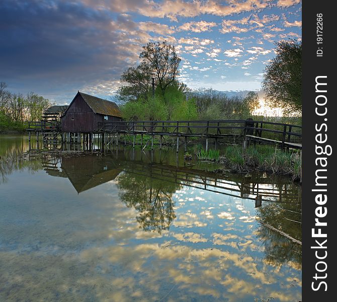 Clouds reflection in water with watermill.