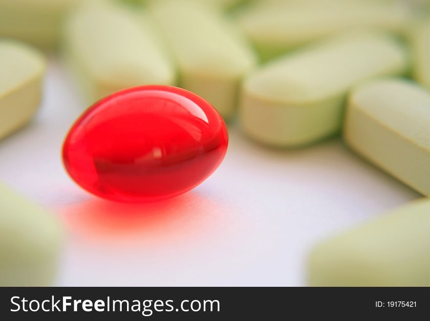 Loose of tablets with a red tablet on a forward background