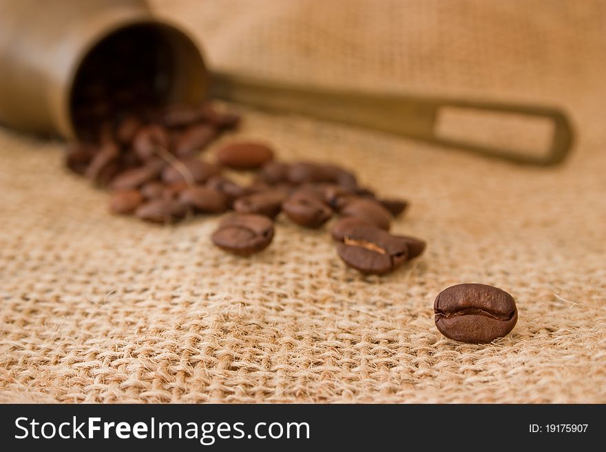 Coffee beans in a coffee pot on burlap sack background