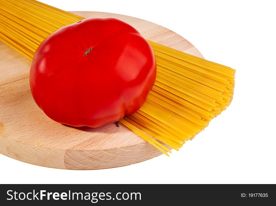 Uncooked italian spaghetti with tomato on wooden board. Uncooked italian spaghetti with tomato on wooden board.