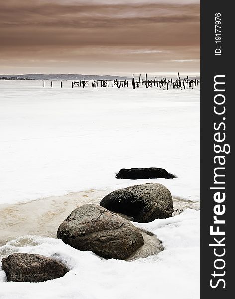 Pier And Stones In Frozen Sea