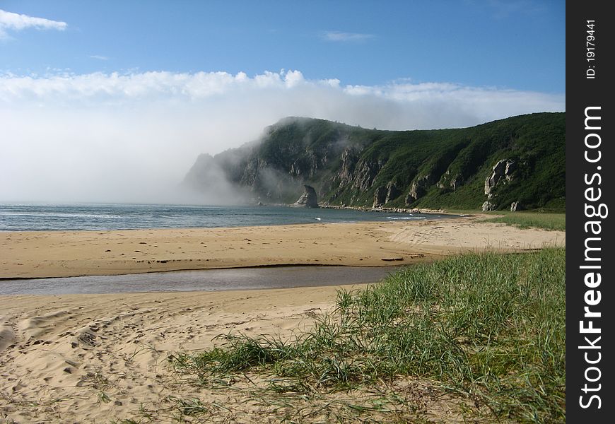 Sea coast in a sunny day and with fog over water