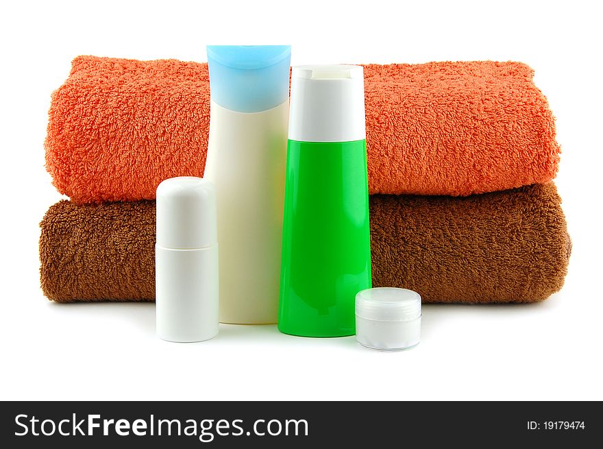 Cosmetic bottles with bath towels isolated on a white background