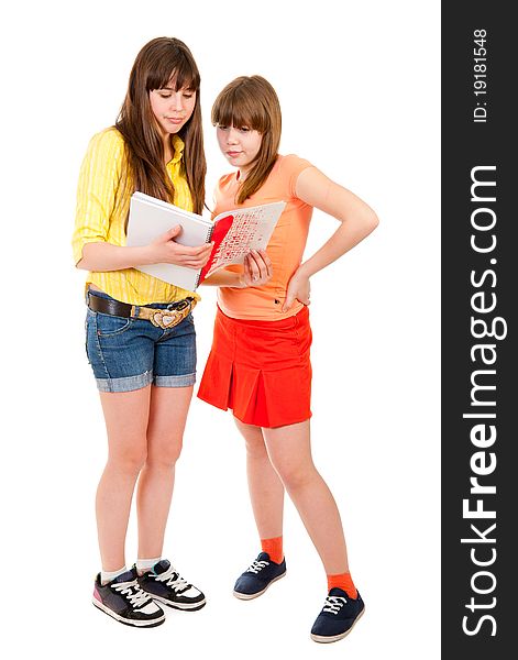 Two schoolgirls teenagers read something in a notebook isolated on white