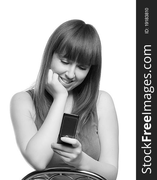 Black-and-white portrait of the long-haired girl with a thoughtful smile looking at phone. Black-and-white portrait of the long-haired girl with a thoughtful smile looking at phone