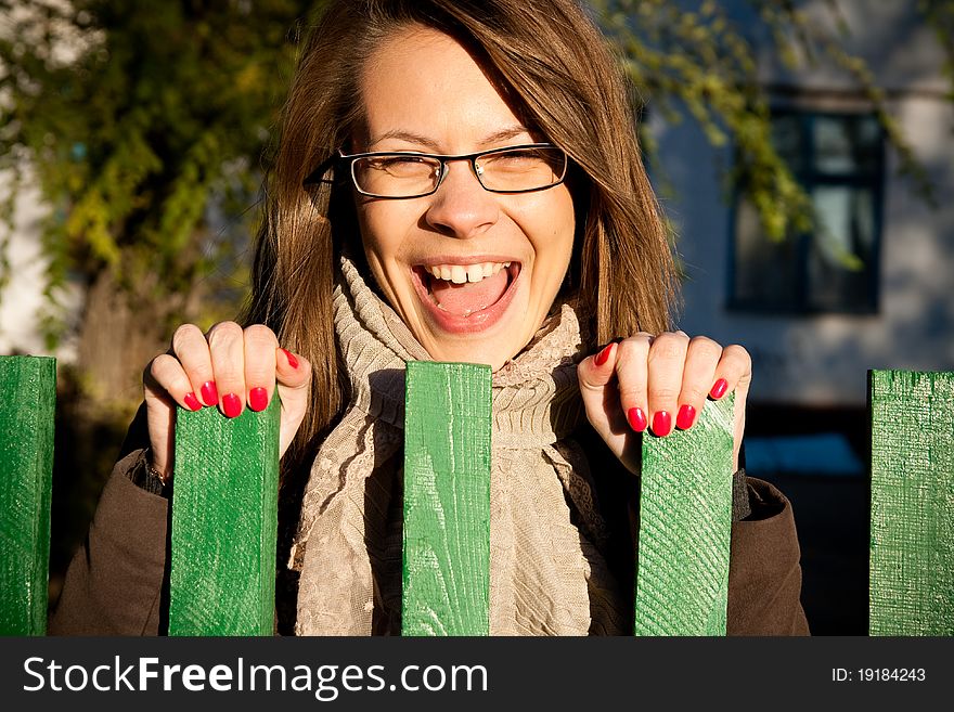 Teenage girl is laughing at green fence on the street. Teenage girl is laughing at green fence on the street.