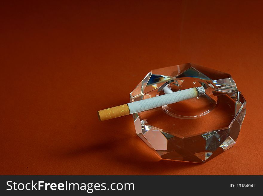 A burning cigarette put on a crystal ashtray. A burning cigarette put on a crystal ashtray