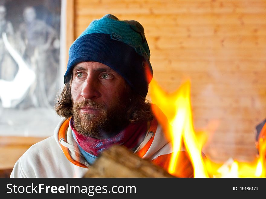 A man with long hair near a fire. A man with long hair near a fire