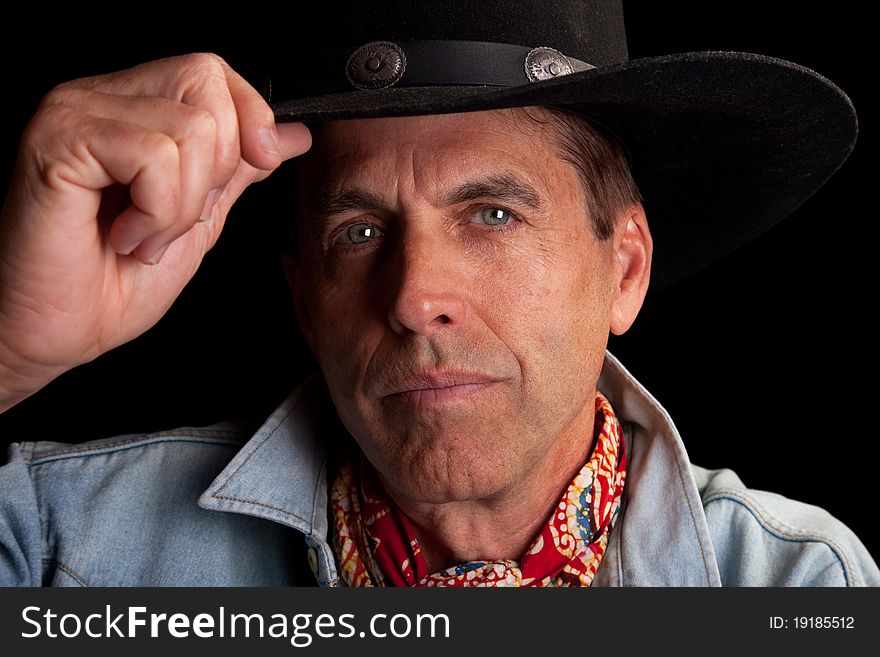 Closeup portrait of a handsome cowboy tipping his hat in salute.