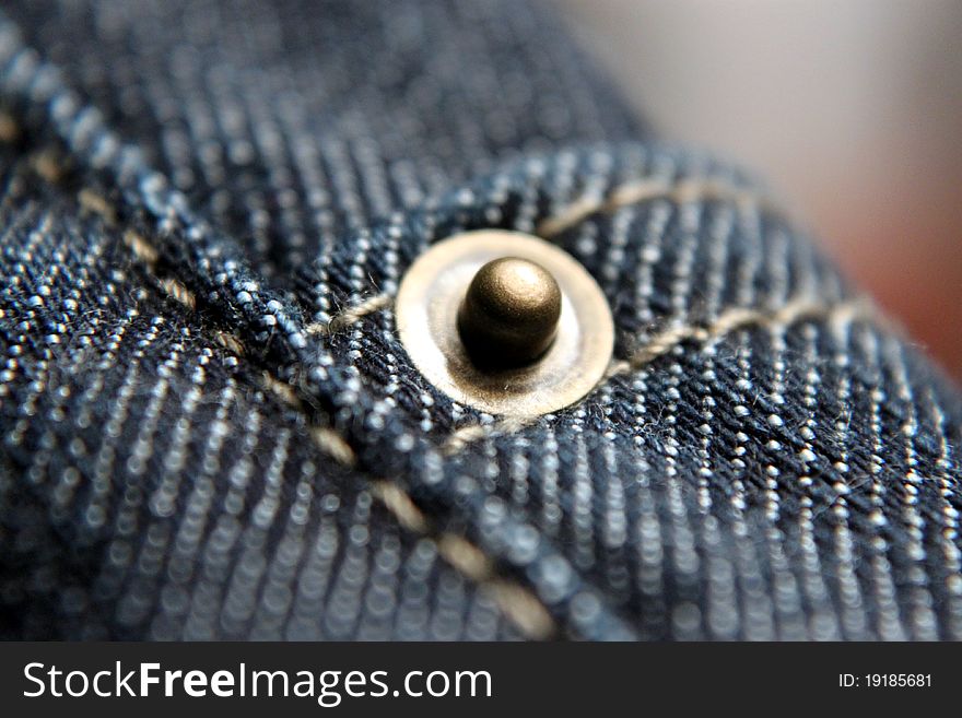 Close-up of a rivet on a pair of blue jeans. Close-up of a rivet on a pair of blue jeans