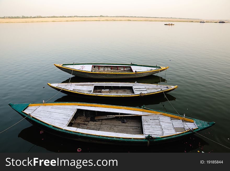 Wooden country boats tied in a row on the bank of river ganga. These boats are used by pilgrims and tourists visiting Varanasi in India. Wooden country boats tied in a row on the bank of river ganga. These boats are used by pilgrims and tourists visiting Varanasi in India.