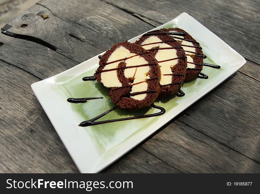 Three pieces of chocolate ice cream cake topped with hot fudge on a flat green dish.
