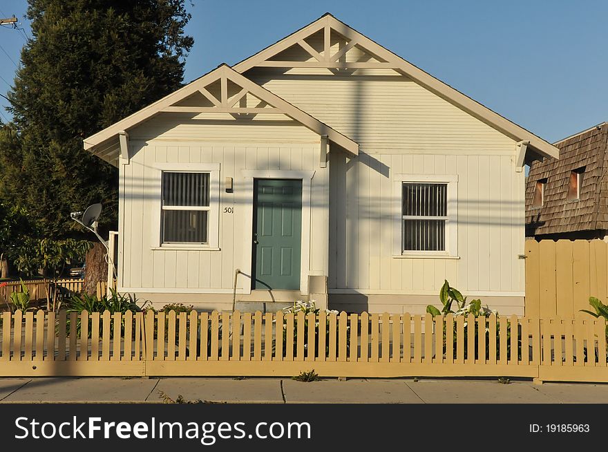 House surrounded by trees and grass with blue sky.