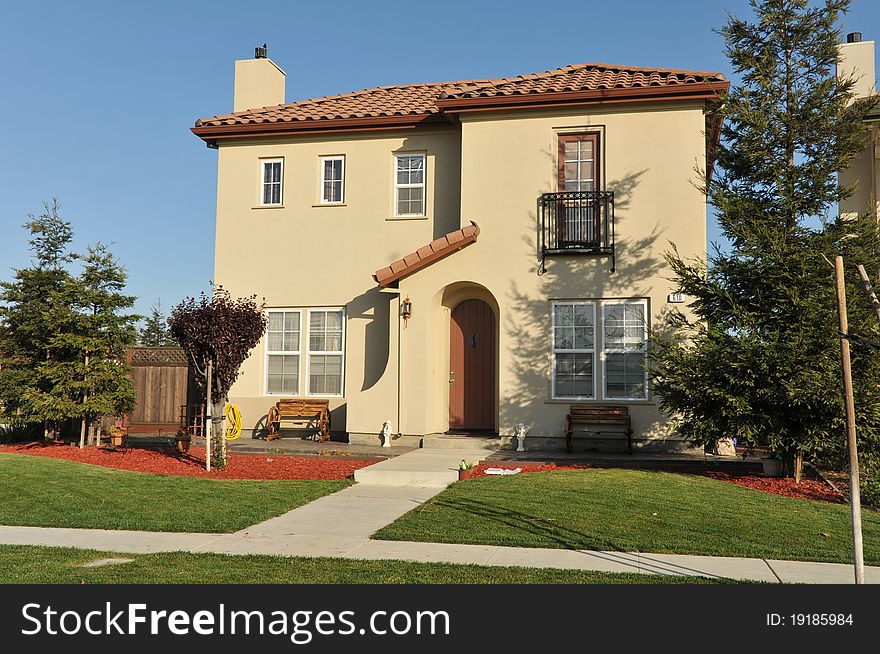 House surrounded by trees and grass with blue sky.