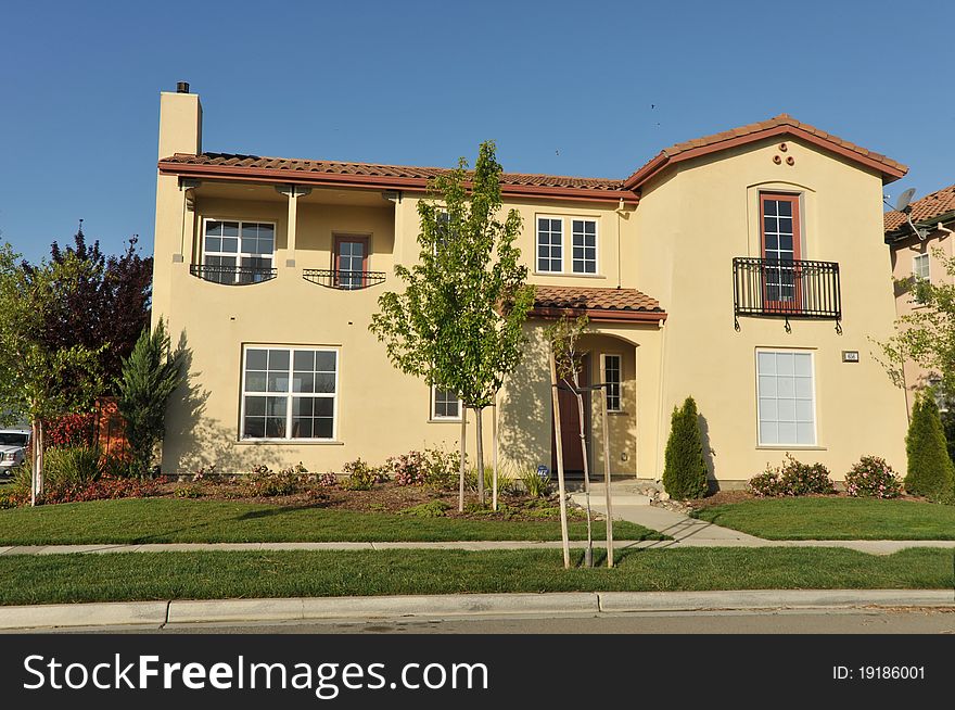 House surrounded by trees and grass with blue sky.