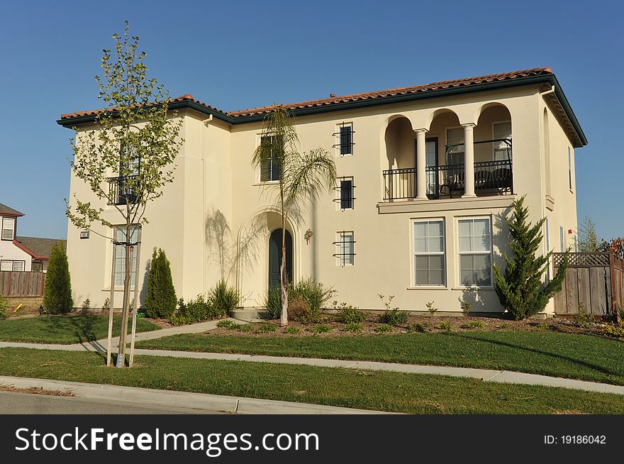 House surrounded by trees and grass with blue sky.