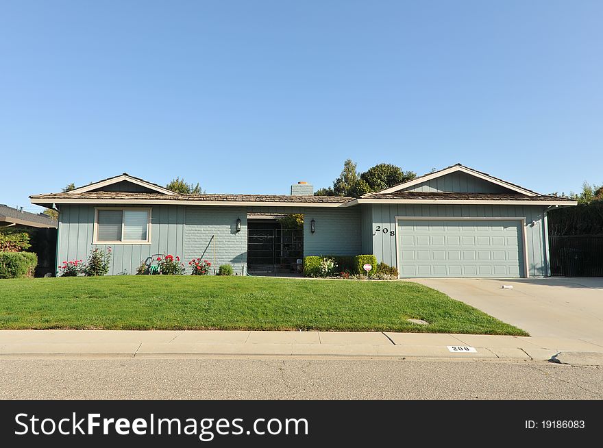 House surrounded by trees and grass with blue sky.