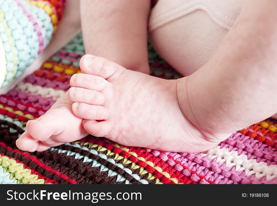 Cute newborn baby girls feet and toes on a striped blanket. Cute newborn baby girls feet and toes on a striped blanket