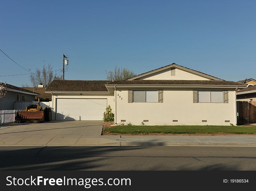 House surrounded by trees and grass with blue sky.