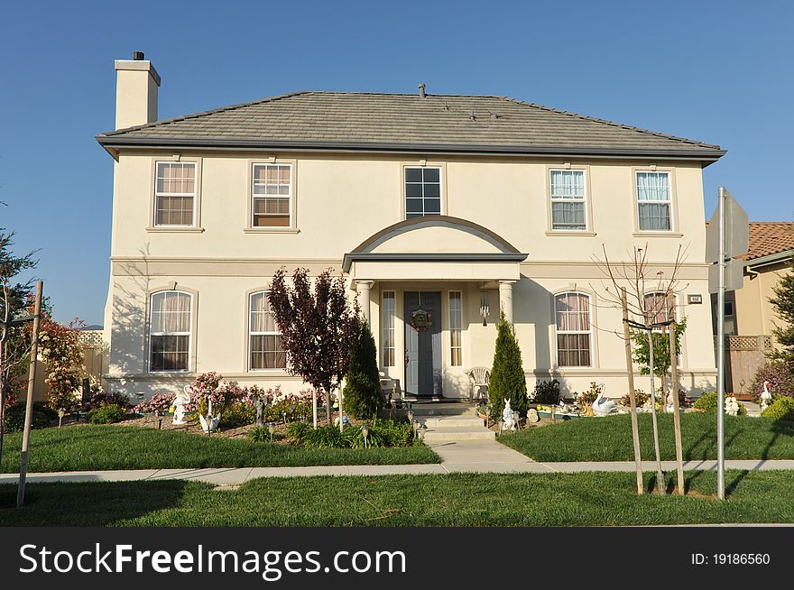 House surrounded by trees and grass with blue sky.