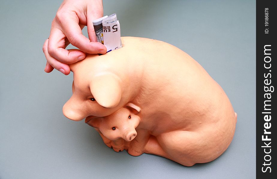 Puting euro money into pig coin box