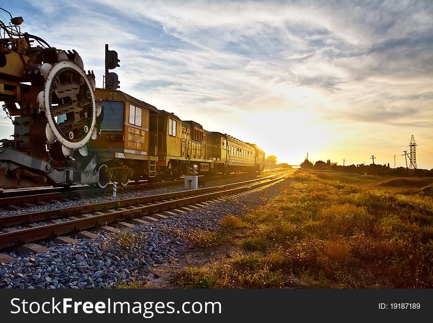 Train locomotive with industrial mechanism traveling during sunset