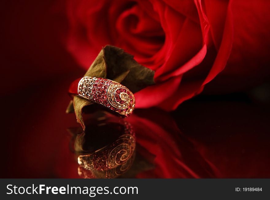 Ring with diamonds & red rose on the bacground