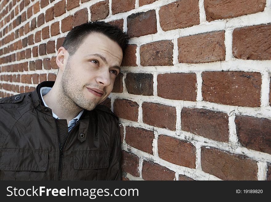 Young man in fron of the brick wall and view on the facade of the old brick wall, Prague.