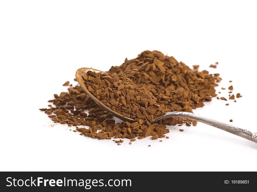 Instant coffee granules in spoon over white