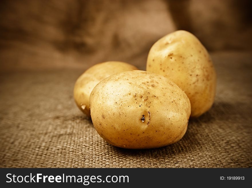 Fresh potatoes on the brown sacking background