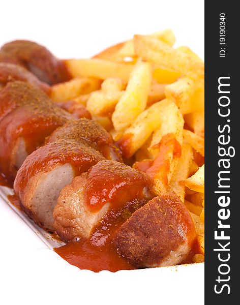 A bowl with curried sausage and chips in front of white background