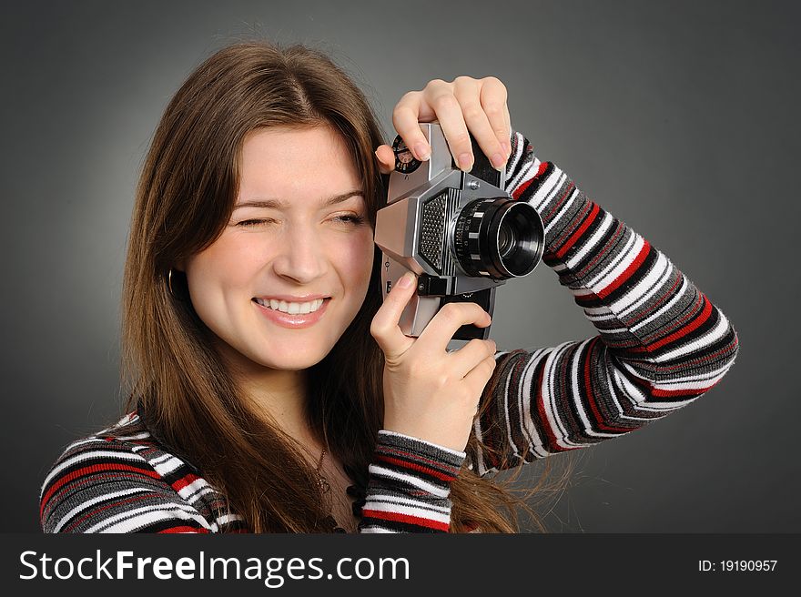Pretty woman with vintage camera on a grey background. Pretty woman with vintage camera on a grey background