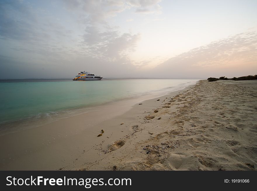 Tropical beach at dusk with sunset and boat in the background. Tropical beach at dusk with sunset and boat in the background