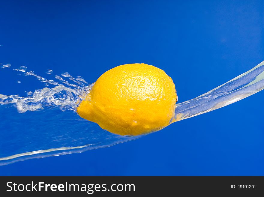 Fresh lemon in the splashes of water on a blue background