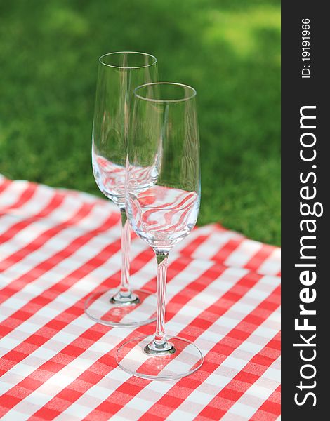 Two empty glasses on the checkered cloth in the garden. Two empty glasses on the checkered cloth in the garden