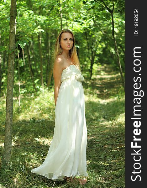 Blond girl in long dress in the summer forest. Blond girl in long dress in the summer forest