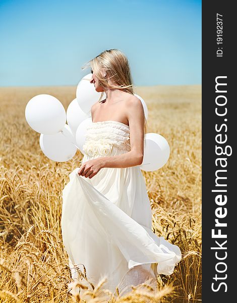 Blond smiling girl with white balloons in the field. Blond smiling girl with white balloons in the field