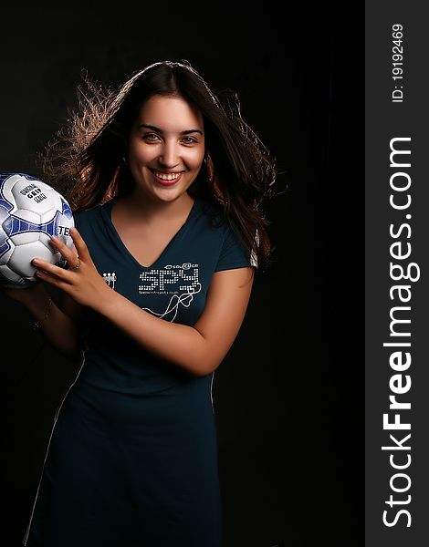 Girl with a football on the black background. Girl with a football on the black background