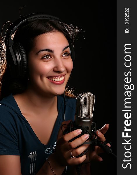 Singin' girl with a microphone and head-phones on the black background