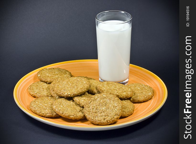 A close up of plain biscuits, and a glass of milk on an orange plate. A close up of plain biscuits, and a glass of milk on an orange plate